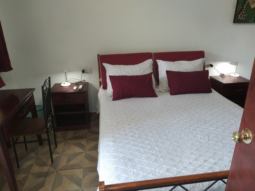 Queensized bed with red pillows and white comforter